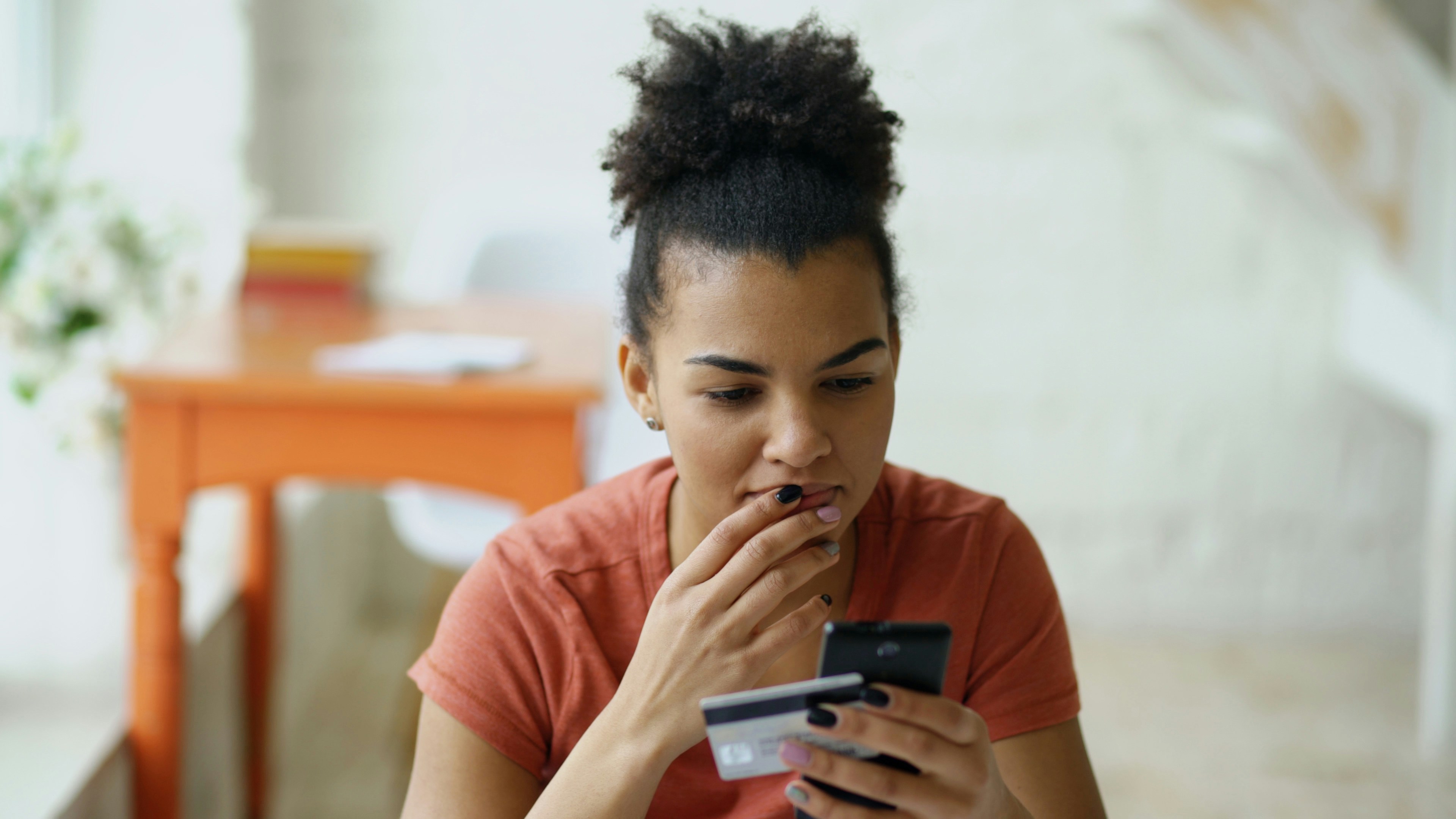Beautiful happy mixed race woman online banking using smartphone shopping online with credit card at home